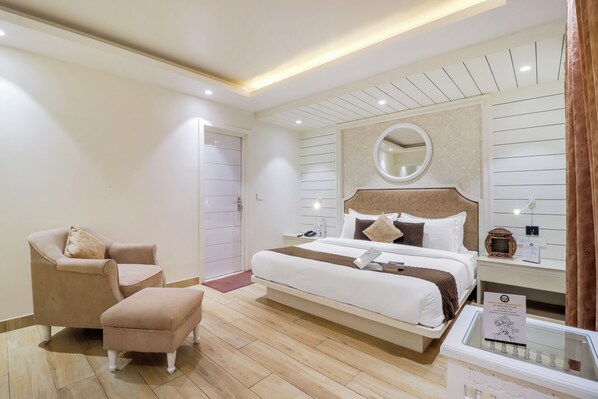 A modern bedroom with a bed, a chair, a small table, and a nightstand.