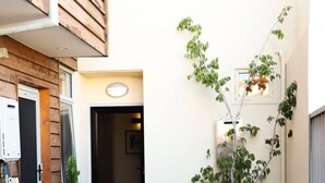 A narrow outdoor corridor with a wooden door, a potted plant, and a wall-mounted light fixture. - Ellen Fremantle City Centre - Walk everywhere. Secure free parking. (Fremantle)