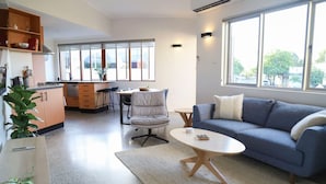 A modern living room with a sofa, a coffee table, a dining area with chairs, a kitchen with cabinets, and a large window providing natural light. - Ellen Fremantle City Centre - Walk everywhere. Secure free parking. (Fremantle)