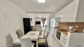 Een moderne keuken met witte kasten, een zwarte koelkast en een houten aanrecht.