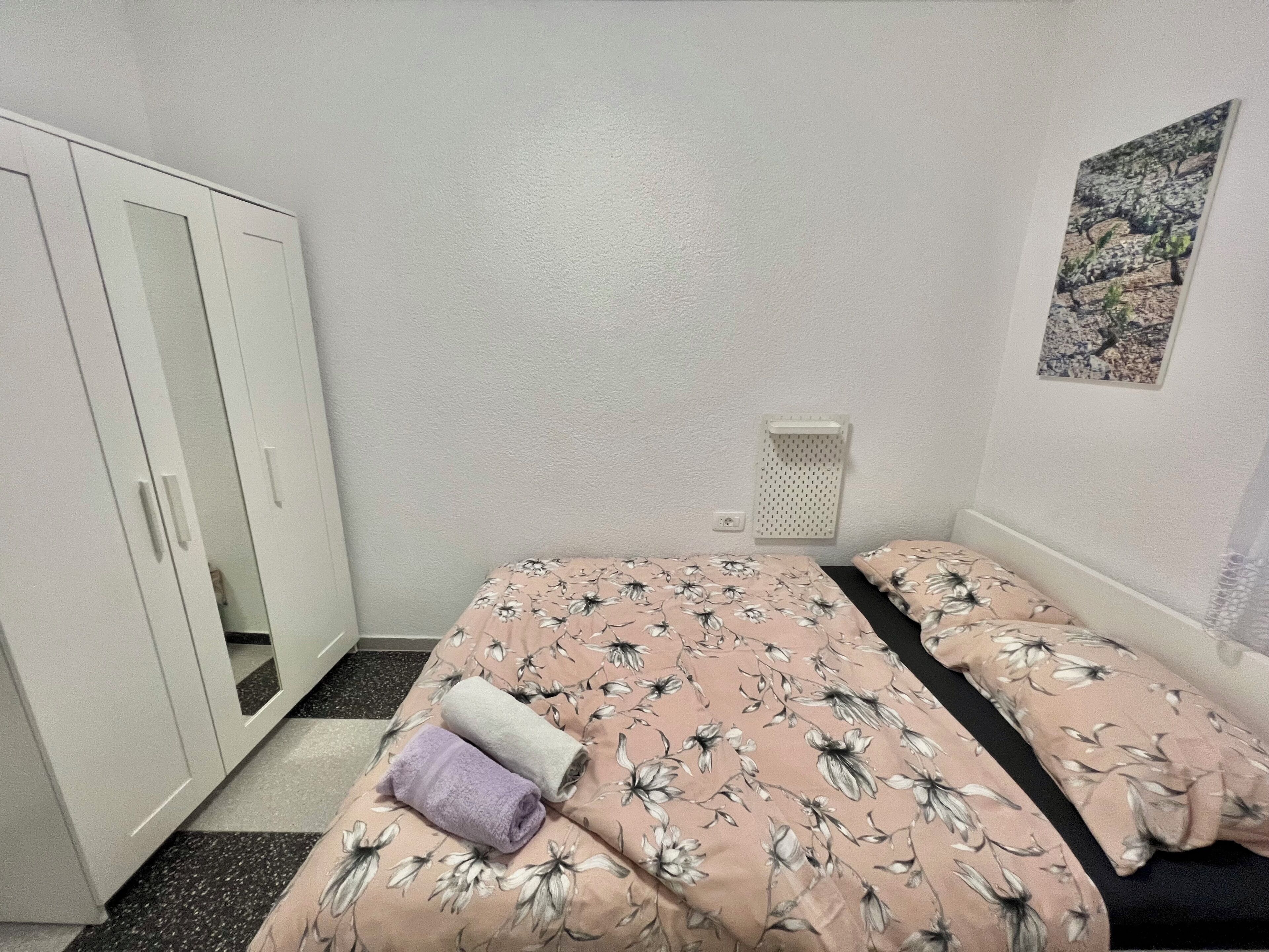 A bedroom with a bed, two pillows, a wardrobe, and a wall-mounted radiator.