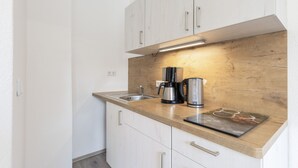 Una cocina funcional con cubierta de madera, cafetera y hervidor.