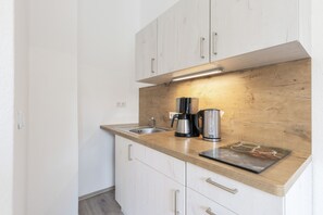 Eine kleine Küche mit einer Holz Arbeitsplatte, Edelstahlgeräten und weißen Schränken.