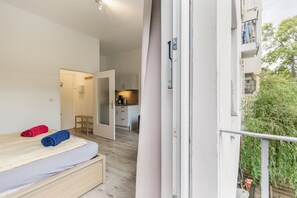 A bedroom with a bed, a wooden bench, and a view of a balcony with greenery.