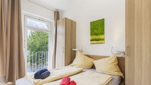 Una habitación de hotel con cama, ventana y un cuadro en la pared.