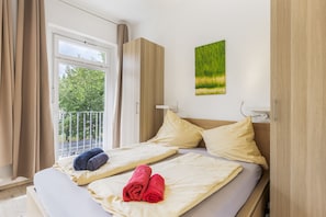 Ein Hotelzimmer mit einem Bett, einem Fenster mit Vorhängen und einem Gemälde an der Wand.
