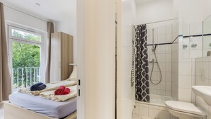 Una habitación de hotel con cama, ventana, ducha y baño.