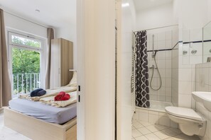 Ein Hotelzimmer mit einem Bett, einem Fenster, einer Dusche und einer Toilette.