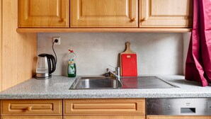 A kitchen with wooden cabinets, a stainless steel sink, a kettle, a cutting board, and a dishwasher. - Apartment 'C' in Miltenberg (Miltenberg)