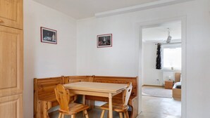 A corner dining area with wooden furniture, two framed pictures on the wall, and a view into another room with a radiator and a window. - Apartment 'C' in Miltenberg (Miltenberg)