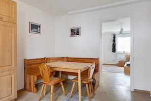 A corner dining area with wooden furniture, two framed pictures on the wall, and a view into another room with a radiator and a window. - Apartment 'C' in Miltenberg (Miltenberg)