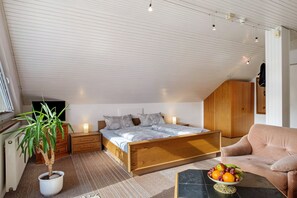 Une chambre avec un lit en bois, une plante en pot, un panier de fruits et un canapé.
