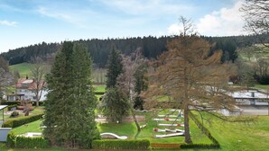 Ein Wohngebiet mit einem großen Baum, einem gepflegten Rasen und einem Wald in der Ferne.