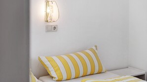 A single bed with a striped pillow and a bedside table with a lamp. - Apartment 'Belchen, 59qm' with Wi-Fi (Schönwald im Schwarzwald)