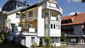 A multi-story residential building with balconies, a garage, and a driveway. - Apartment 'Belchen, 59qm' with Wi-Fi (Schönwald im Schwarzwald)