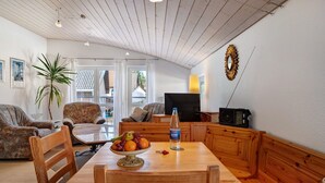 A living room with a wooden table, chairs, a TV, and a radio. - Studio 'Brend, 48qm' with Balcony and Wi-Fi (Schönwald im Schwarzwald)