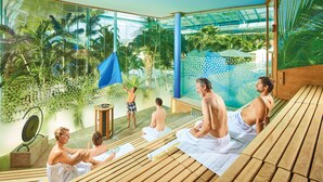 A spa area with wooden benches, a glass wall, and a view of palm trees. - Studio 'Brend, 48qm' with Balcony and Wi-Fi (Schönwald im Schwarzwald)
