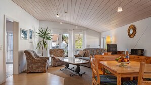 A spacious living area with a wooden ceiling, a dining table with chairs, a sofa, and a television. - Studio 'Brend, 48qm' with Balcony and Wi-Fi (Schönwald im Schwarzwald)