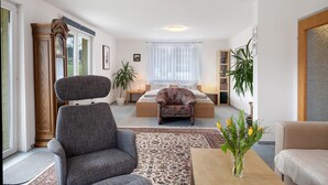 A living room with a sofa, armchair, and a bed with a nightstand. - Studio 'Hörnleberg, 80qm' with Balcony and Wi-Fi (Schönwald im Schwarzwald)