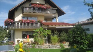 Una casa de dos pisos con balcón, jardín y una bandera.