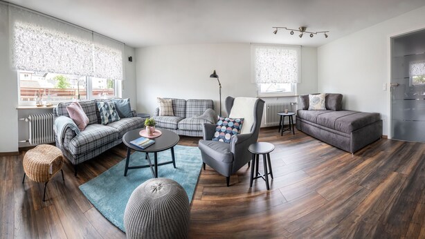 Una sala moderna con sofá, sillón, mesa de centro y mesa de comedor.
