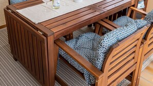 Una mesa de comedor de madera con cojines de estampado azul, un camino de mesa blanco y un jarrón decorativo.
