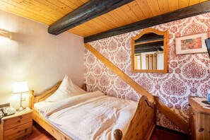 A wooden bed with a headboard, a bedside table with a lamp, and a mirror on the wall.