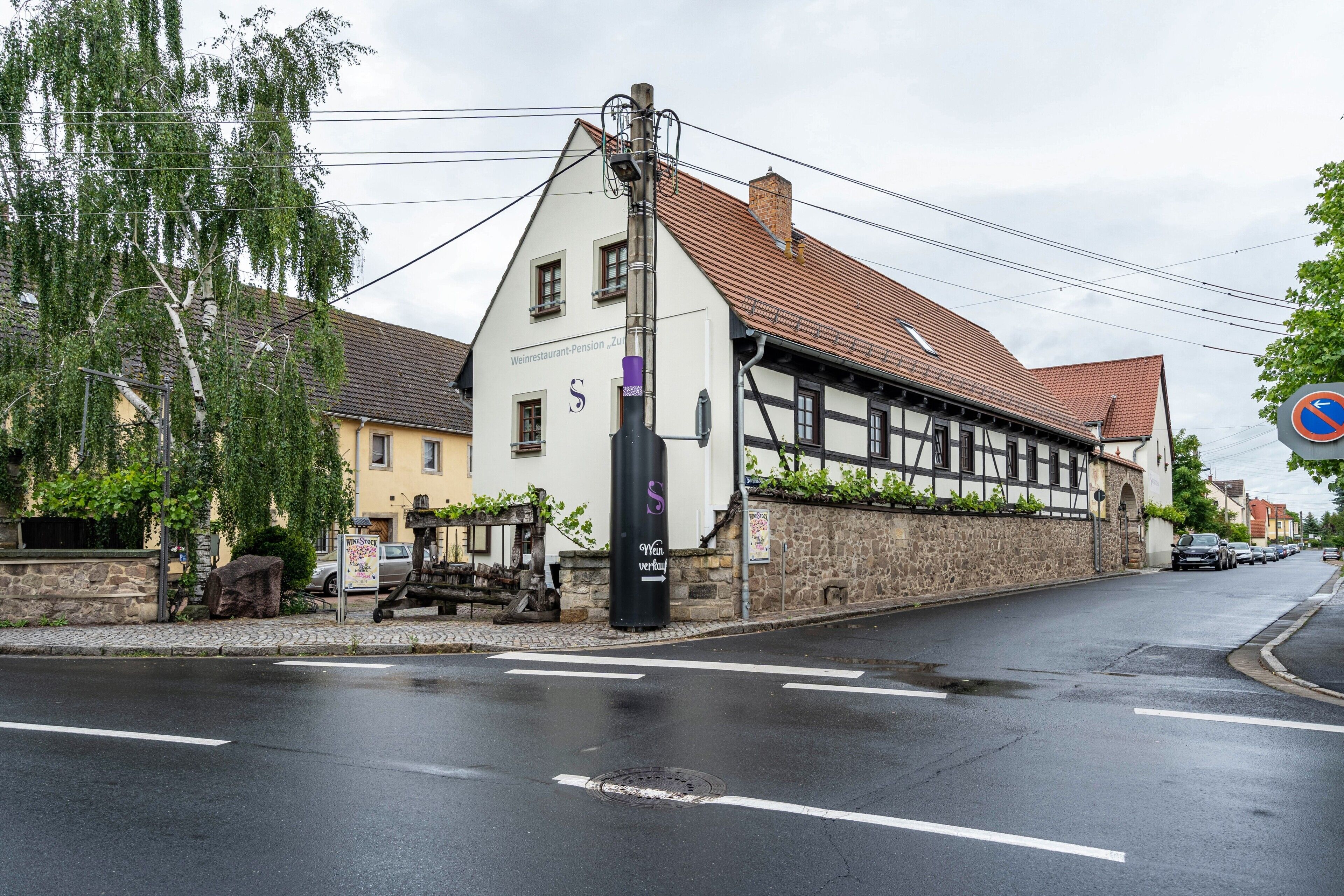 A building with a sloped roof, a signboard, and a street with cars.