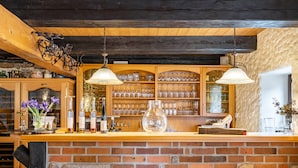Un coin bar au style rustique, avec des étagères en bois, des lampes suspendues et un mur en briques.