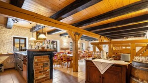 A rustic interior with exposed wooden beams, a brick bar area, and a dining space with wooden tables and chairs. - Room 'Im Weinrestaurant 6' with Shared Garden and Wi-Fi (Coswig)