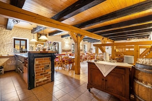 A rustic interior with exposed wooden beams, a brick bar area, and a dining space with wooden tables and chairs. - Room 'Vinotel 11' with Shared Garden, Wi-Fi and Air Conditioning (Coswig)