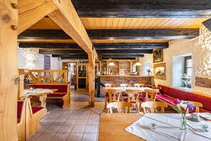 Un interior de madera con una zona de bar, bancos de madera y mesas.