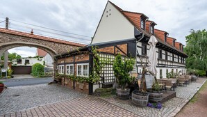 Ein traditionelles Fachwerkhäuschen mit einer im Hintergrund sichtbaren Steinbogenbrücke.