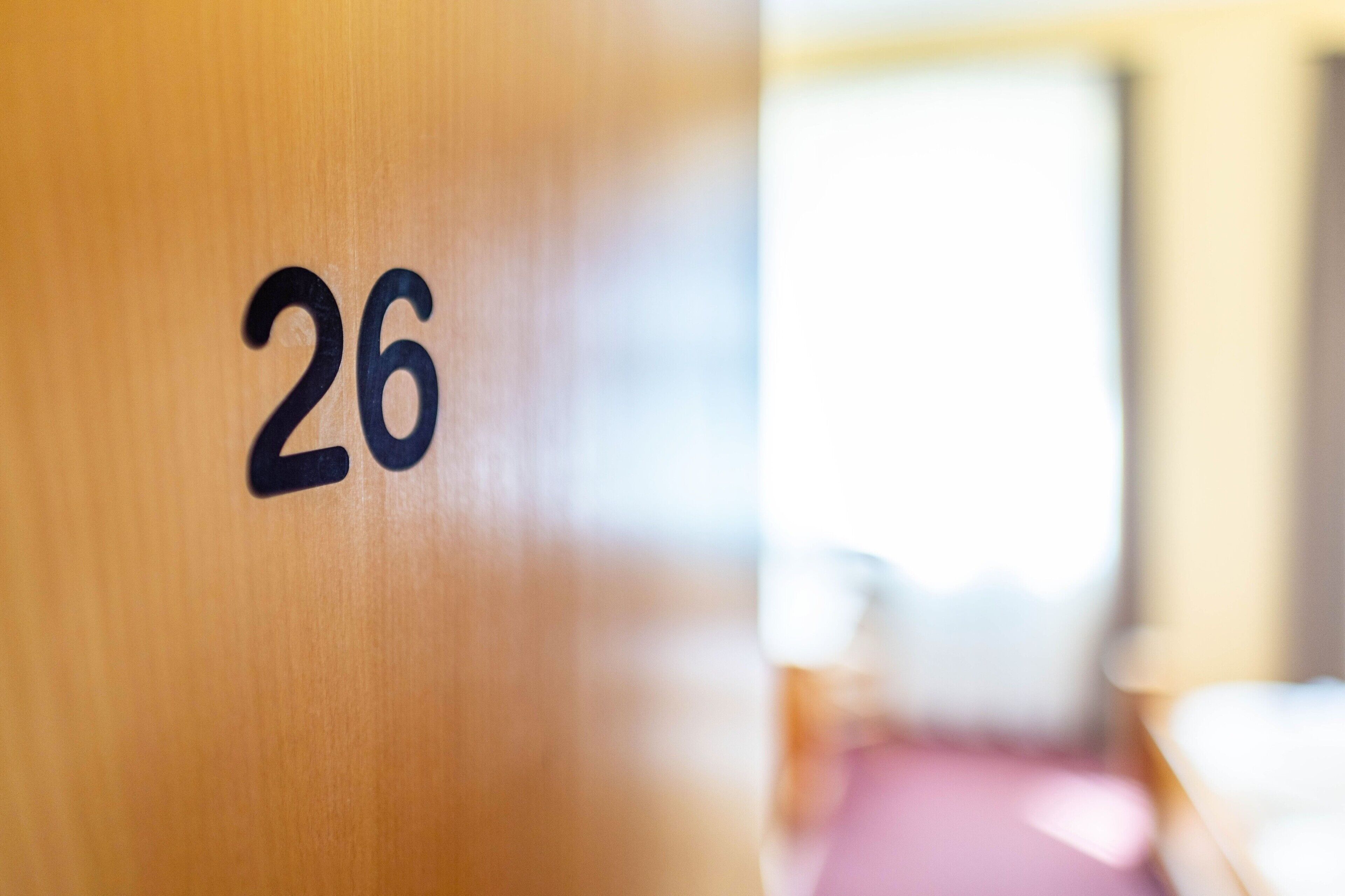 Primer plano de una puerta de madera con el número 26.