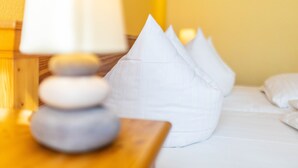 Ein Bett mit weißen Kissen und einem Nachttisch aus Holz mit einer Lampe.