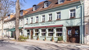 Ein Gebäude mit einem Schild, auf dem 'Zum Jungen Fritz' steht, und einem gut erkennbaren Eingang.