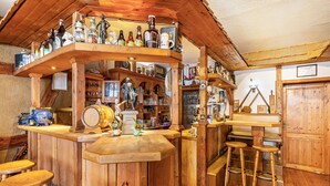 Eine Bar mit Holztresen, Hockern, Flaschenregalen und verschiedenen Bartools.