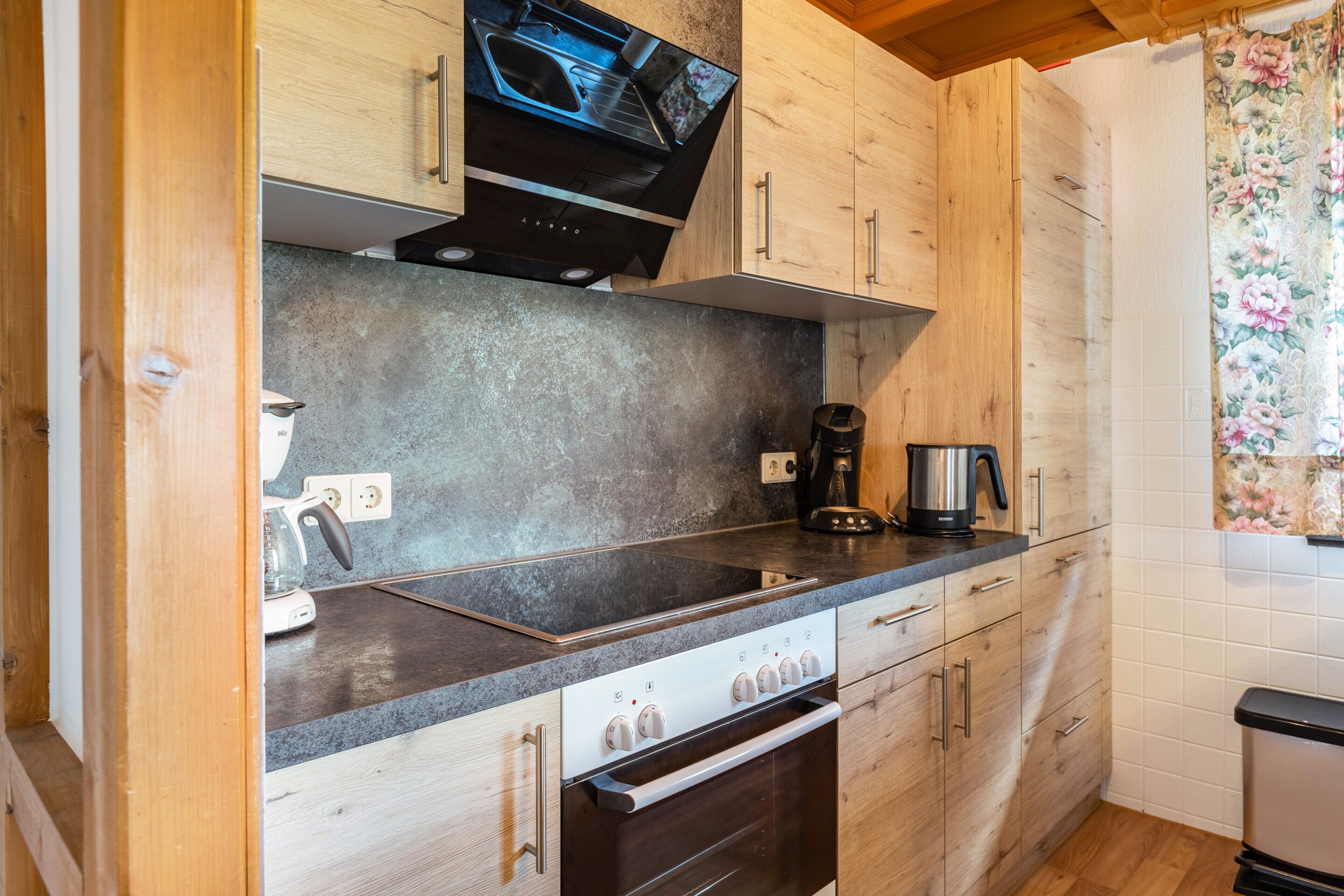 Eine Küche mit Holzausstattung, einer Edelstahlspüle, einem Backofen und einer Kaffeemaschine.
