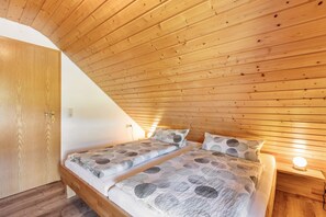 Ein Schlafzimmer mit zwei Betten, Holzboden und einem Nachttisch mit Lampe.