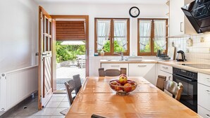 A kitchen with a dining table, a bowl of fruit, and a view of the outdoors. - Apartment 'Talblick' with Mountain View, Private Terrace and Wi-Fi (Wolfach)