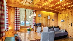 A wooden cabin interior with a dining table, sofa, and curtains. - Apartment 'Talblick' with Mountain View, Private Terrace and Wi-Fi (Wolfach)