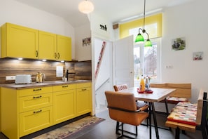 A kitchen with yellow cabinets, a wooden countertop, and a dining area with a table and chairs.