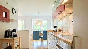 Eine Küche mit Essbereich, einer Uhr an der Wand und Blick ins Freie.