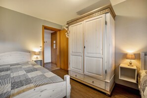 Une chambre à coucher comprenant un lit, des tables de chevet, une armoire et une porte donnant sur une autre pièce.