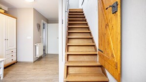 A wooden staircase leading to a landing with a white wall and a radiator.