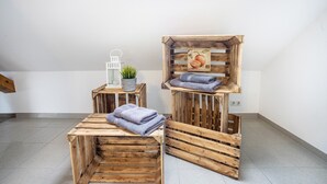 A room with a wooden bench, a small table with a plant, and a wooden crate with towels.