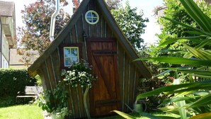 A wooden cabin with a clock, a window, and a door.