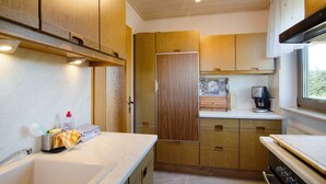 Une cuisine compacte avec des meubles en bois, un four encastré et une machine à café.
