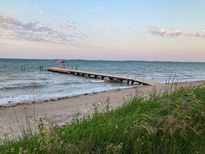 A beach with a wooden pier extending into the water, a small shelter at the end, and grassy vegetation in the foreground. - Apartment 'Ferienwohnung Ankerleicht' with Shared Terrace, Shared Garden and Wi-Fi (Steinbergkirche)