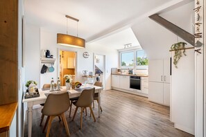 A modern kitchen with a dining area, wooden flooring, and a view of the outdoors. - Apartment 'Ferienwohnung Ankerleicht' with Shared Terrace, Shared Garden and Wi-Fi (Steinbergkirche)